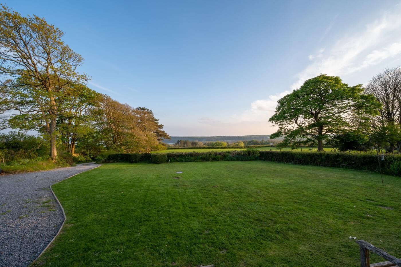 A well-maintained grassy lawn with a gravel path leading to a wooden fence.