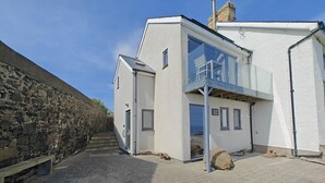 A modern building with a stone wall on one side, a paved entrance, and a sign reading "Center Waves". - 2 Bed in Craster (oc-c25099) (Dunstan)