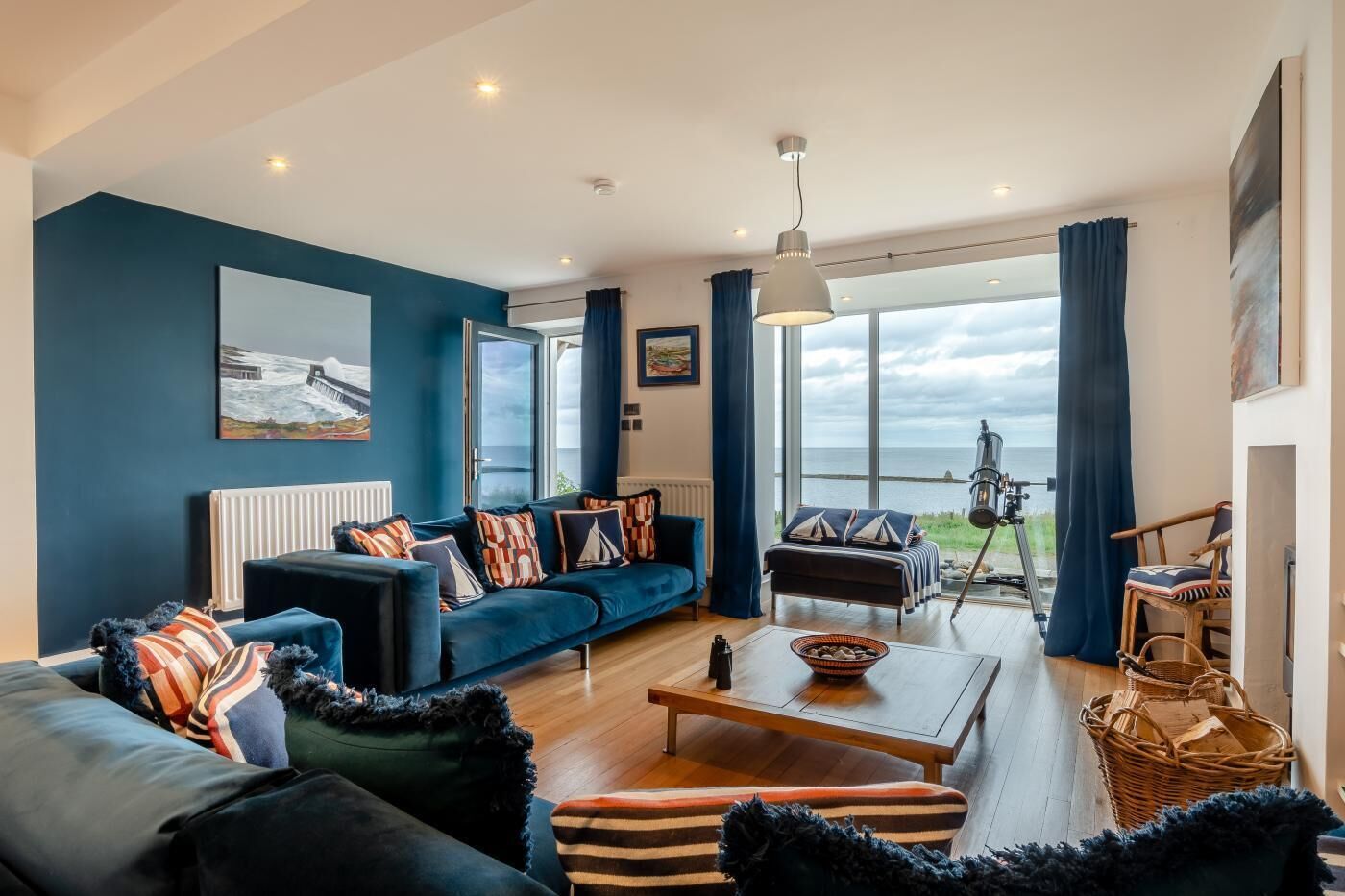 A modern living room with a sofa, coffee table, and a view of the sea through large windows.