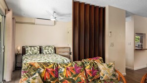 Une chambre à coucher comprenant un lit, un canapé, un ventilateur de plafond, une armoire en bois et une petite table avec une lampe.