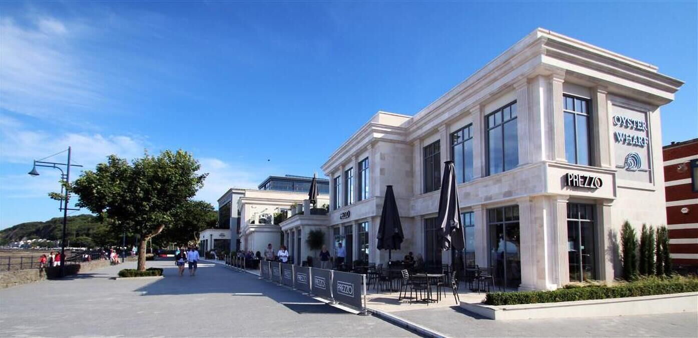 A coastal building with a restaurant named "Oyster Wharf" and "Prezzo" on the ground floor.