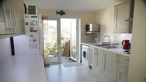 A kitchen with a washing machine, a microwave, and a red kettle. - 2 Bed in Mumbles (oc-hh120) (The Mumbles)