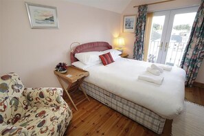 A hotel room with a bed, a bedside table, a chair, a window with curtains, and a wall with a framed picture. - 2 Bed in Mumbles (oc-hh120) (The Mumbles)