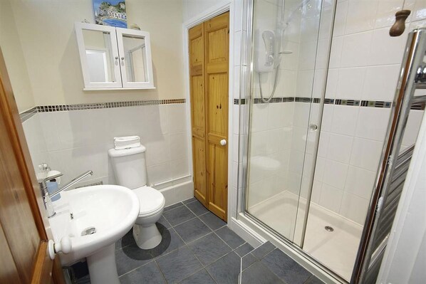 A bathroom with a toilet, sink, shower, and wooden door. - 2 Bed in Mumbles (oc-hh120) (The Mumbles)
