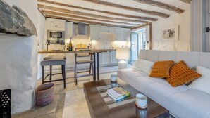 A modern living room with a white sofa, a coffee table, and a kitchen in the background. - 1 Bed in Harlech (oc-t32043) (Harlech)