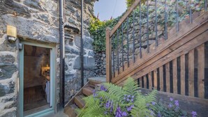 A stone building with a wooden staircase and a door leading to a room. - 1 Bed in Harlech (oc-t32043) (Harlech)