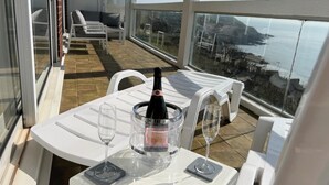 A balcony with a table set for two, a bottle of champagne, and two glasses.