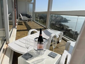 A balcony with a table set for two, a bottle of champagne, and two glasses.