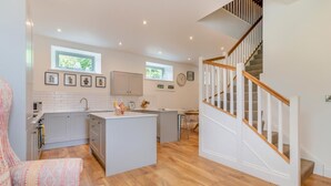 Een moderne keuken met een keukeneiland, houten vloeren en een trap met witte leuningen.