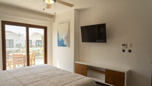 A bedroom with a bed, a TV mounted on the wall, a sliding glass door leading to an outdoor area, and a small wooden cabinet. - 2BR 7 Guests Private Jacuzzi in Monterrico (Taxisco)