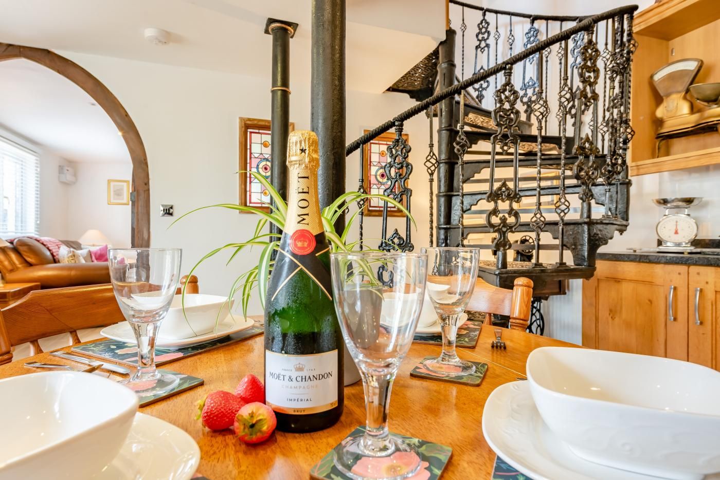 A dining area with a bottle of Moët & Chandon champagne, glasses, strawberries, and a wooden table.