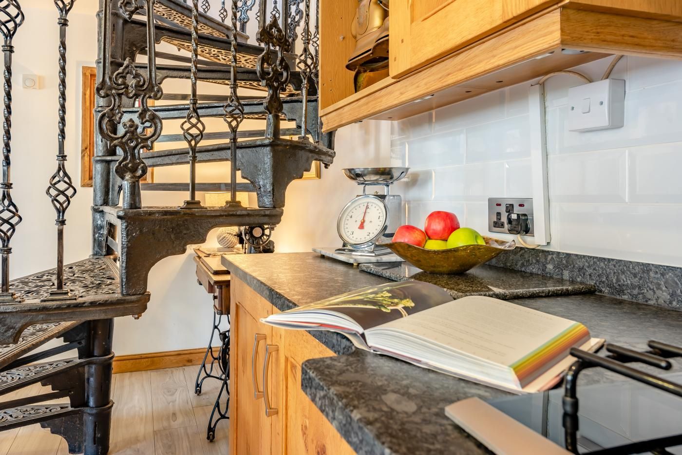 A kitchen with a wooden counter, a scale, and a bowl of fruit.