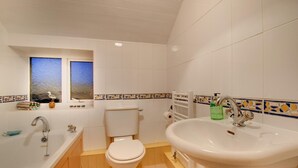 Een badkamer met een bad, een wastafel en een toilet.