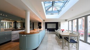 A spacious kitchen with a large island, a dining area with a table and chairs, and a skylight above. - 4 Bed in Blakeney (oc-2070) (Blakeney)