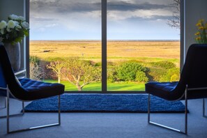A room with two chairs facing a large window overlooking a grassy landscape. - 4 Bed in Blakeney (oc-2070) (Blakeney)