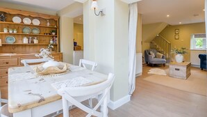 A dining area with a wooden table and chairs, a kitchen with wooden shelves, and a staircase leading to another level. - 2 Bed in Hanworth (oc-h32041) (Hanworth)