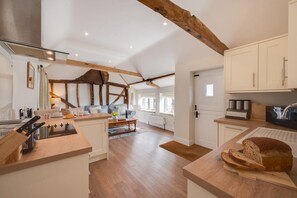 Eine moderne Küche mit Holzbalken, weißen Schränken und einer zentralen Kochinsel.