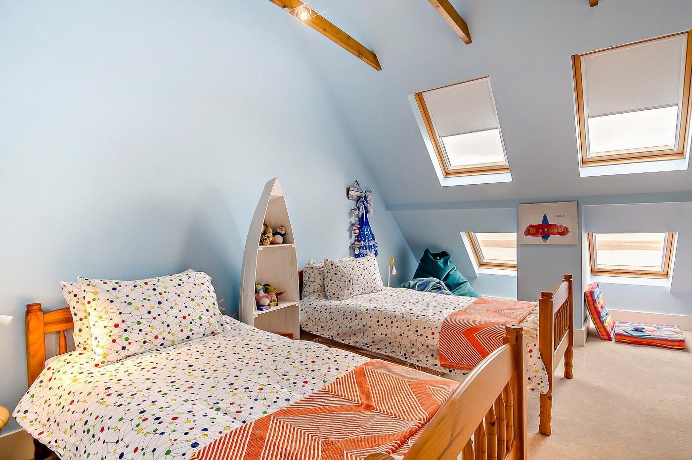 Una habitación con dos camas, una estantería y tragaluces.