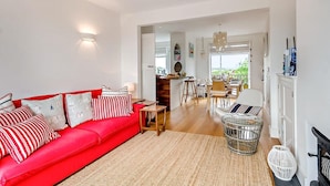 Een ruime woonkamer met een rode bank, een eethoek en uitzicht op de omgeving.