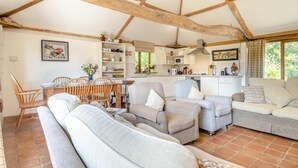 Ein gemütliches Wohnzimmer mit Essbereich, Küche und großen Fenstern.