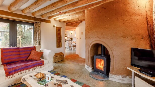 A cozy living room with a stone fireplace, wooden beams, a sofa, and a television. - 2 Bed in Kilmington (oc-c32220) (Kilmington)