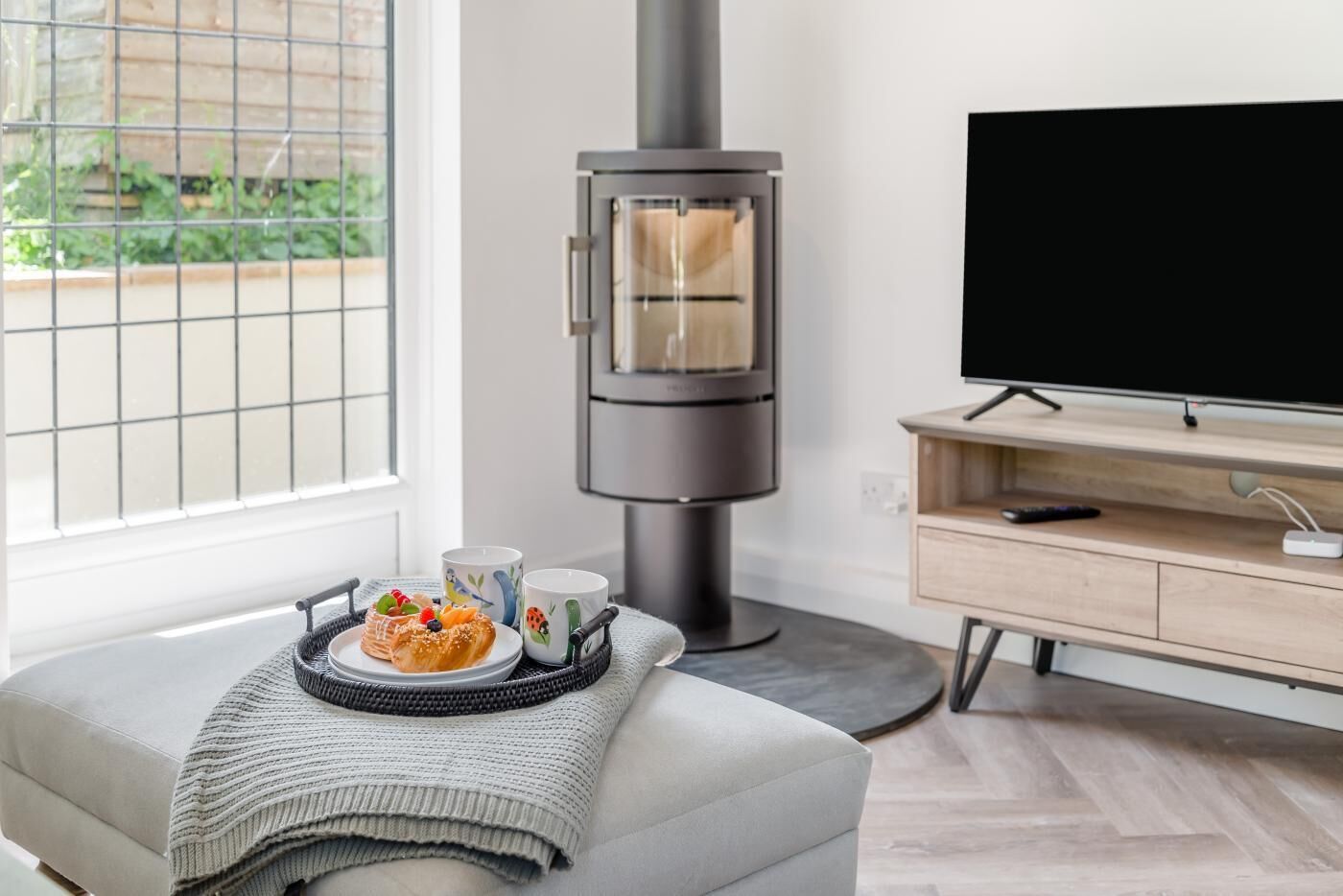 Een moderne woonkamer met een ingebouwde houtkachel, een flatscreen-tv en een eethoek met een schaal gebakjes.