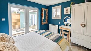 A bedroom with a bed, a desk, a wardrobe, and a view through a sliding door to an outdoor area. - 1 Bed in Beadnell (oc-s32097) (Beadnell)
