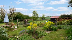Ein Garten mit einer Holzbank, einem Tisch und einer kleinen Gartenhütte.