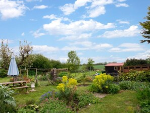 Ein Garten mit einer Holzbank, einem Tisch und einer kleinen Gartenhütte.