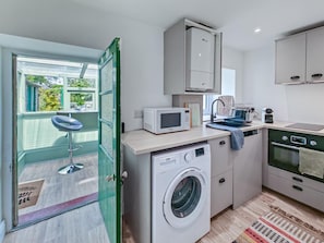 A compact kitchen with a washing machine, microwave, and oven.