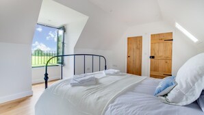 Una camera da letto con un letto, un lucernario, porte in legno e vista su un paesaggio verde.