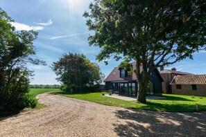 A house with a gravel driveway, a large tree, and a clear sky. - 1 Bed in Sudbourne (oc-tgs) (Sudbourne)