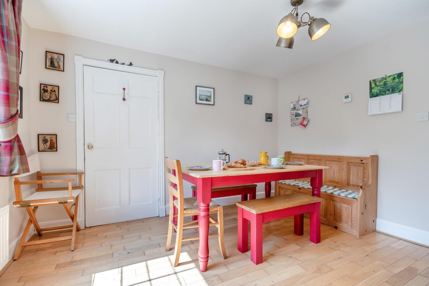 A cozy dining area with a wooden table and chairs, a bench, and a ceiling light fixture.