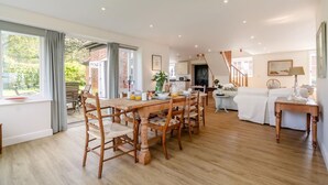 Un amplio espacio habitable con una mesa de comedor, un sofá y una escalera que conduce a un nivel superior.