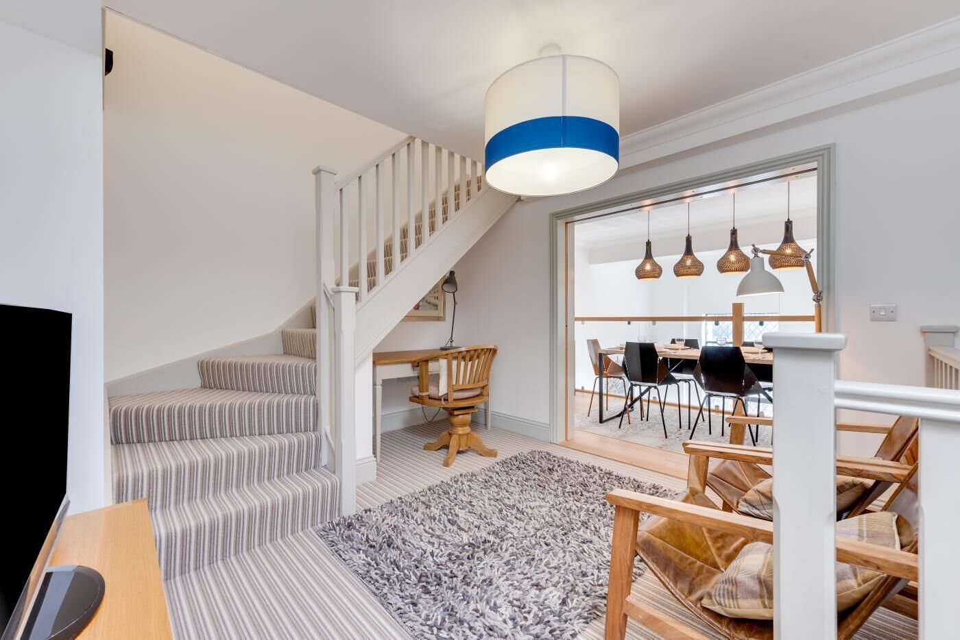 Un intérieur moderne avec un escalier, un coin repas et une grande fenêtre.