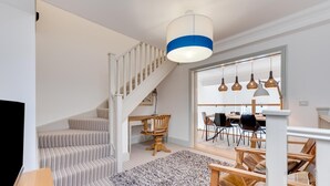 Un interno moderno con una scala, zona pranzo e una grande finestra.