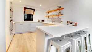 Una cucina moderna con mobili bianchi, un'isola centrale e sgabelli da bar.