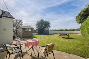 A patio area with a table and chairs, a small shed, and a picnic table. - 2 Bed in Dymchurch (oc-s31998) (Dymchurch)