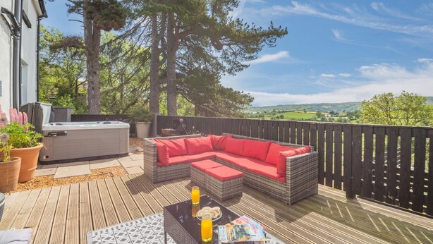 Eine Terrasss mit Korbmöbel-Sofa, Whirlpool und Tisch mit Getränken und Zeitschriften.