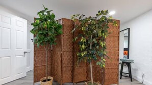 A room with a white door, a brick partition, and two potted plants. - The Gator Den: Perfect for Groups & Families! 3 BR/ 2 Bath (Gainesville)