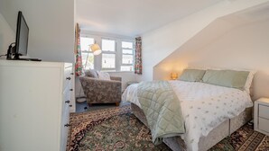 Ein Schlafzimmer mit Bett, Stuhl, Schreibtisch und Fenster.