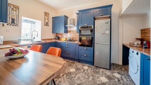 Eine moderne Küche mit blauen Schränken, einem Edelstahlkühlschrank, einem eingebauten Backofen und einer Waschmaschine.