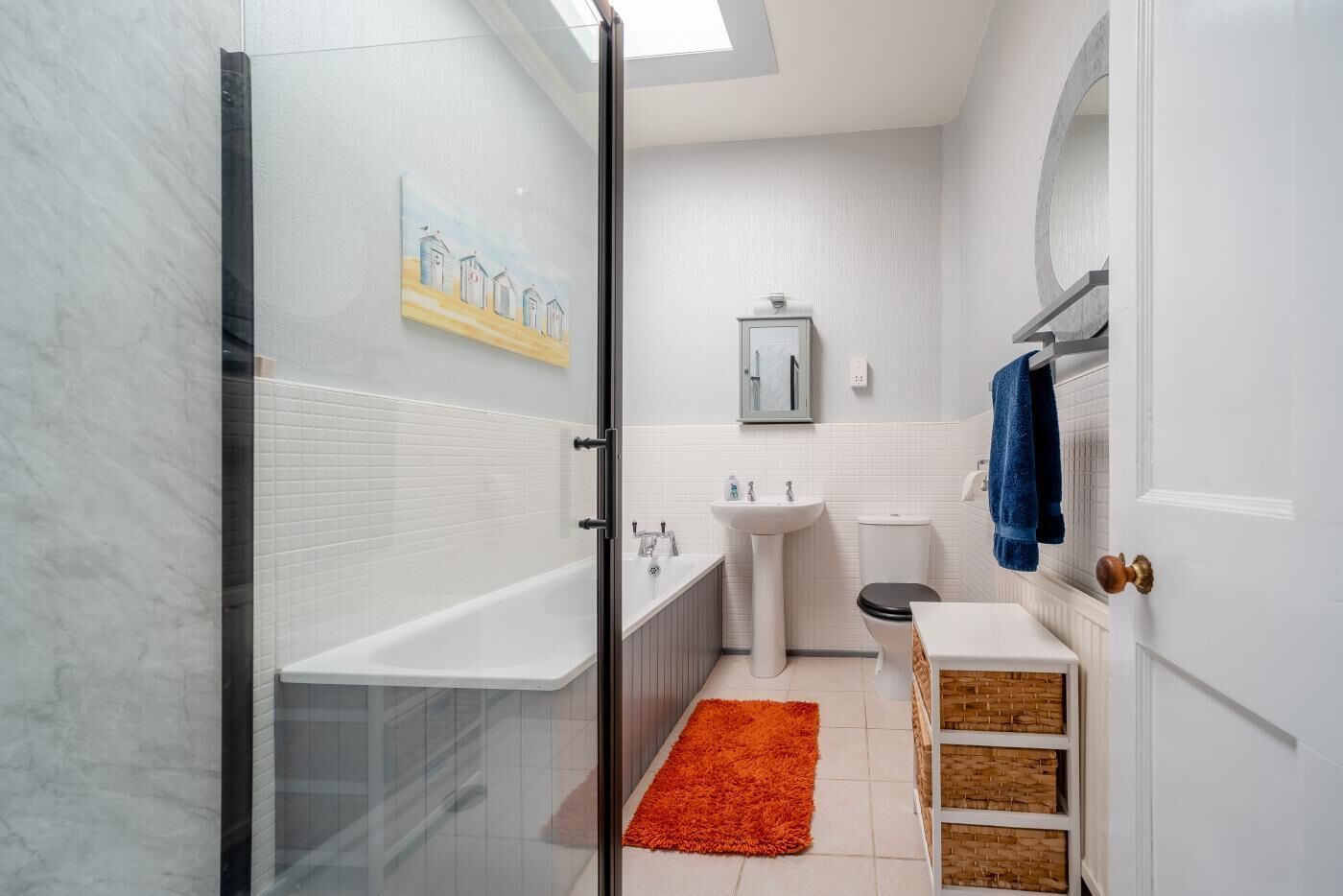 A modern bathroom with a glass shower enclosure, a white sink, and a toilet.