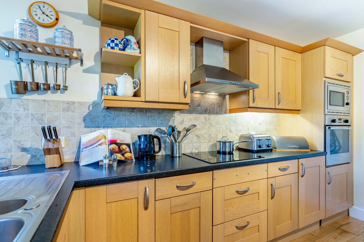 A kitchen with wooden cabinets, a stainless steel range hood, a microwave, and an oven.