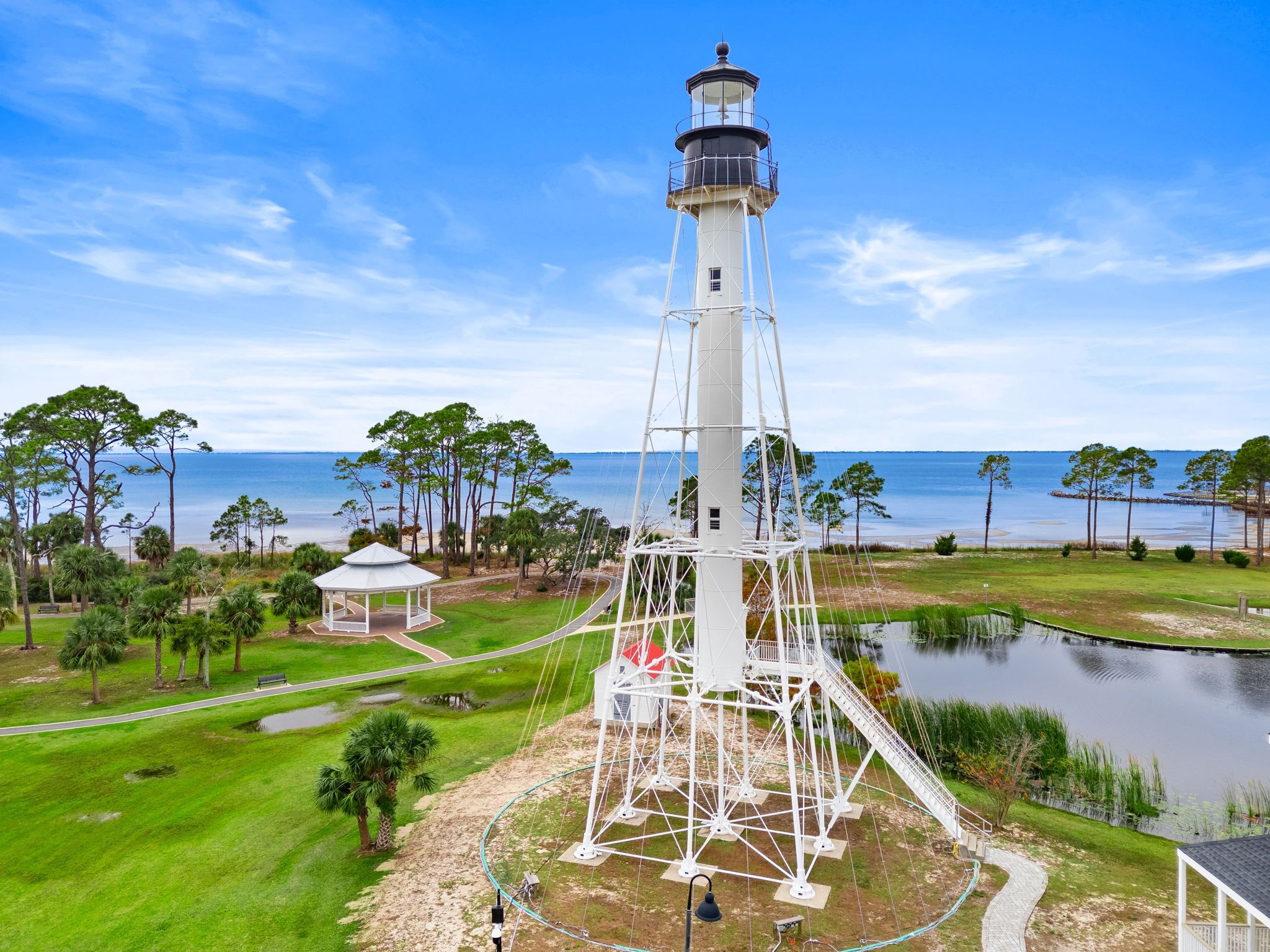 Aerial view showcasing a historic lighthouse landmark near the property, set amid coastal greenery, tranquil ponds, and scenic bay waters—an iconic feature of the surrounding area.