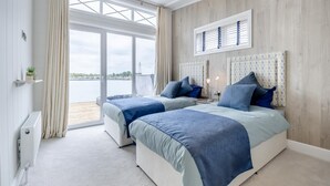 A bedroom with two beds, a large window, and a view of the water. - 2 Bed in Tallington (oc-b32208) (Maxey)