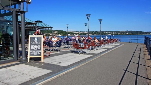 Ein Straßencafé mit Tischen und Stühlen mit Blick auf das Wasser.