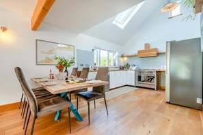 Eine moderne Küche mit Oberlicht, Holzbalken und einem Edelstahl-Kühlschrank.
