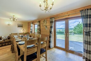 Un coin repas avec une table en bois dressée pour quatre personnes, un canapé et un lustre.