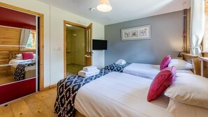 Quarto de hotel com duas camas, uma televisão e porta de acesso a um banheiro.